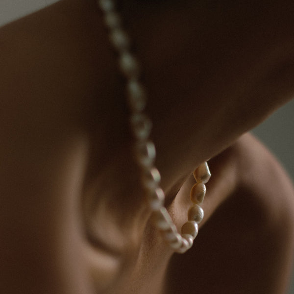 Handcrafted in London, ivory freshwater pearl necklace displayed on woman's neck. Made with responsible and sustainable practices.