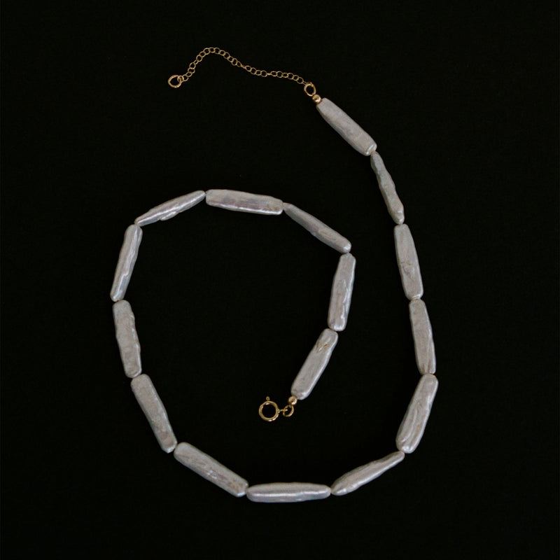 Freshwater pearl necklace with solid 9k gold clasp and chain closure flat lay.