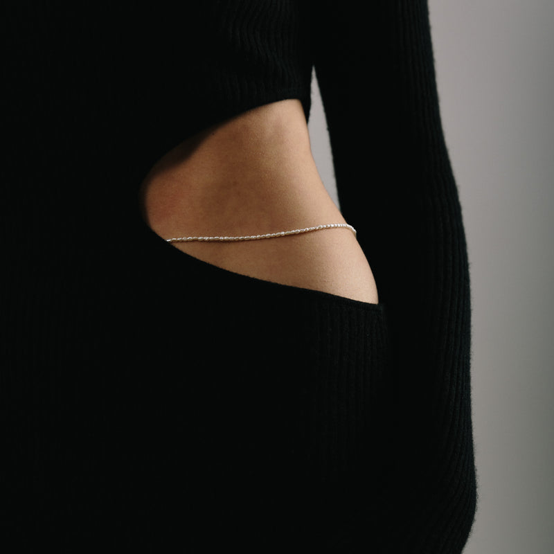 Ethically handmade white freshwater pearl body chain shown on woman's hip